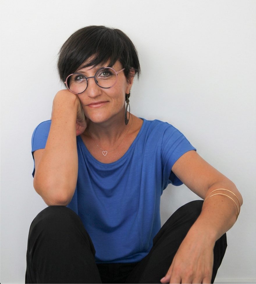 Donna seduta e sorridente, in maglia blu